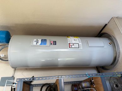 A tall, cylindrical water heater installed in a utility corner.