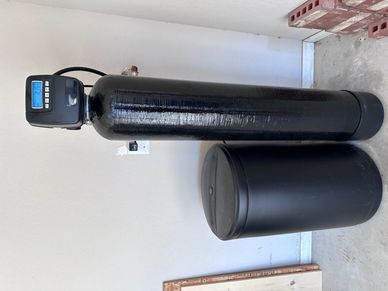 Black water softener system installed indoors.
