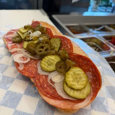 Stacked sub sandwich, with the works pickles, jalapeños , onions pepperoni.
