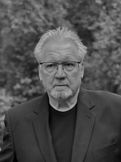 Black and white portrait of an older man with glasses and a beard.