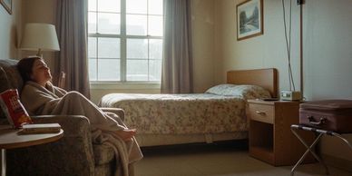 Woman relaxing on a chair wrapped in a blanket in a cozy bedroom.