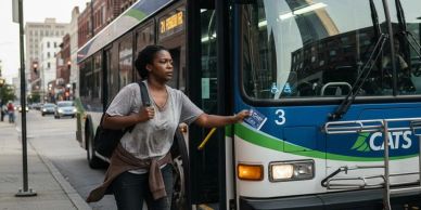 Woman boarding a city bus in urban setting.