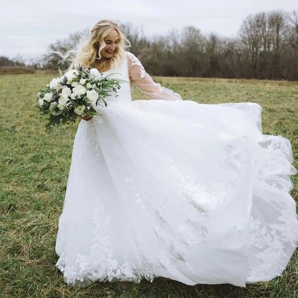 Bride joyfully twirling outdoors in a white wedding gown with a bouquet.