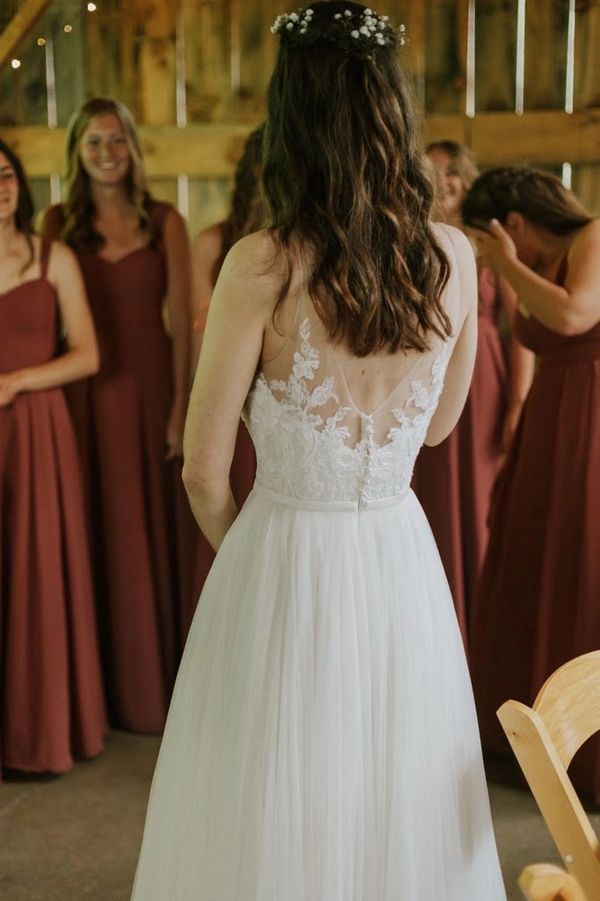Bride in a white lace dress with bridesmaids in rust-colored gowns.