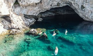 People entering to a cave with SUPs