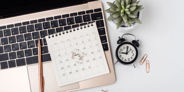 the keyboard of a laptop, with a small calendar, a clock and a plant.
