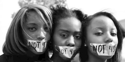 Three women with "NOT 4 SALE" taped over their mouths in protest.