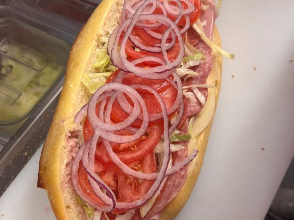 Sub sandwich with salami, tomato, lettuce, and red onion.