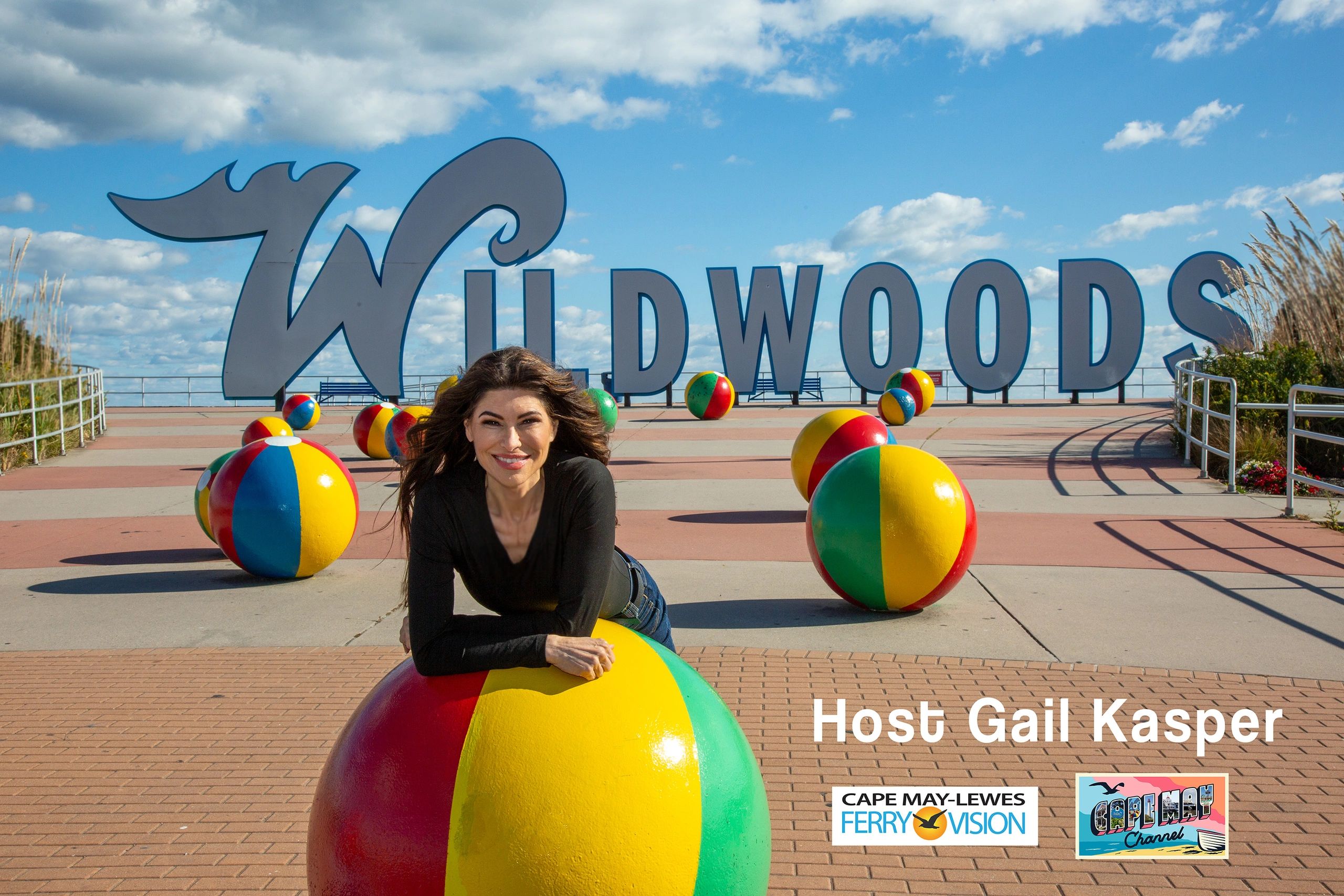 Host Gail Kasper leans on the giant beach ball in front of the iconic Wildwoods sign in Wildwood, NJ