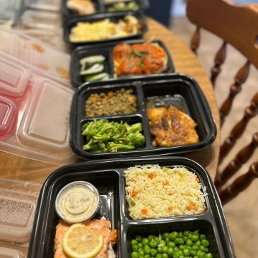 Multiple meal prep containers with various foods arranged on a table.