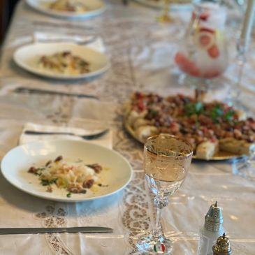 A table set with plates of pasta, pizza, and a glass of wine.