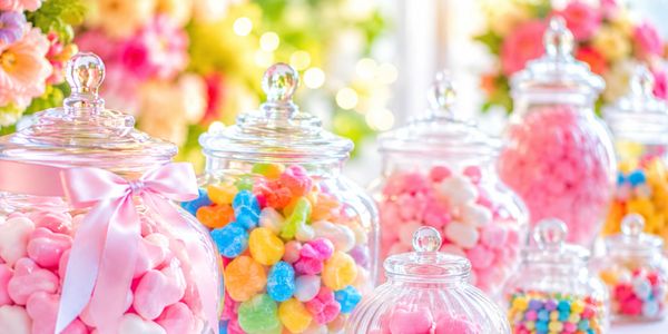 Colorful candies in glass jars with a bright, floral background.