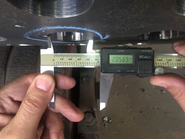 Digital caliper measuring metal part diameter.
