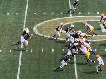 Football quarterback prepares to throw pass behind his offensive line.