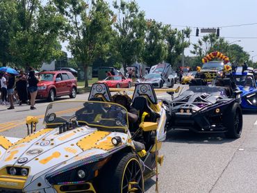 A lively parade of custom sports cars and spectators on a sunny day.