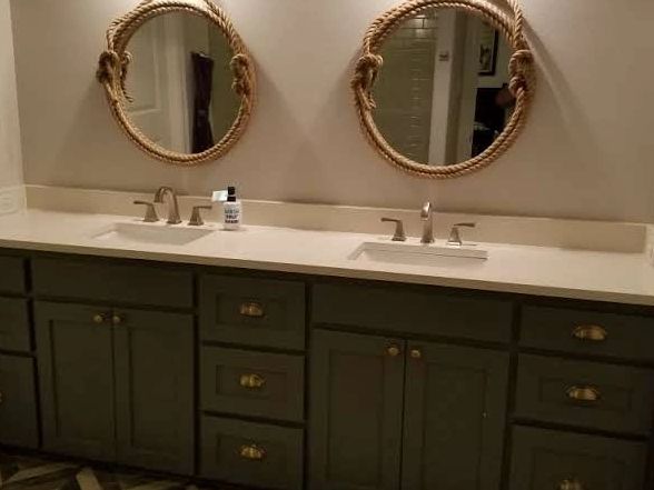 Double bathroom vanity with rope-framed round mirrors and chevron floor tiles.