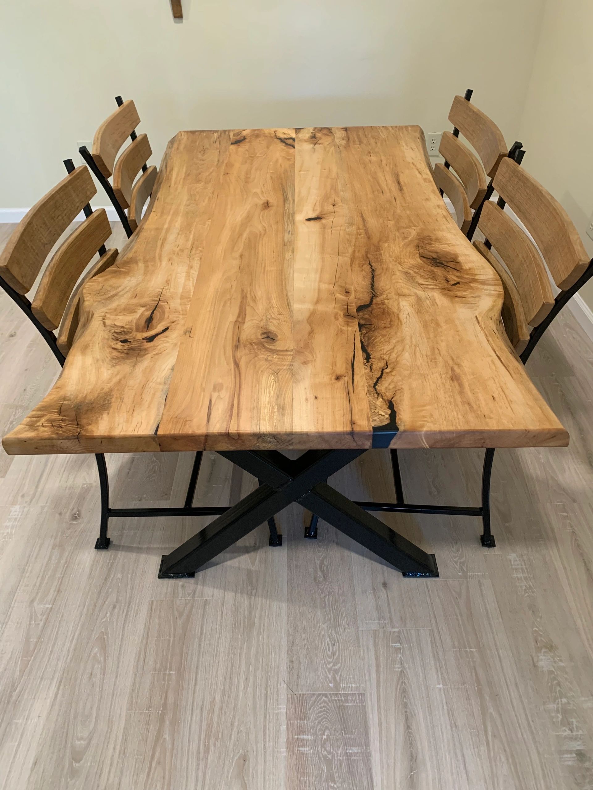 Wooden dining table with six chairs in a minimalist room.