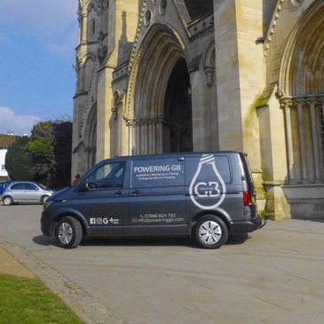 Electric van parked near a historic building.