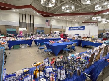 Indoor event with information booth and tables covered in blue cloths.