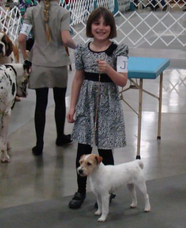 Young girl smiling while showing her dog at a dog show.