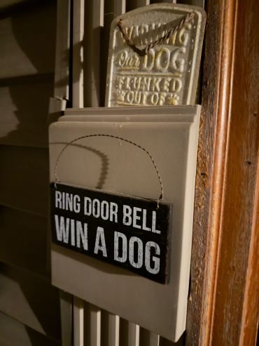 A humorous sign says "Ring door bell, win a dog."