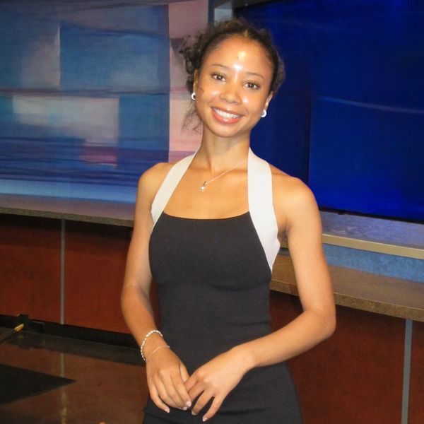 Woman in black dress posing in a modern studio setting.