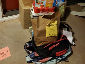 Donation items sitting in front of a door. Donation bag and yellow card visible.