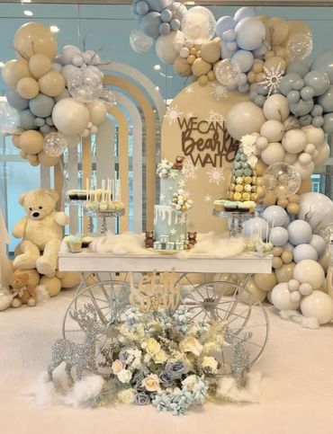 Winter-themed party setup with balloons, teddy bears, and a decorated cake.