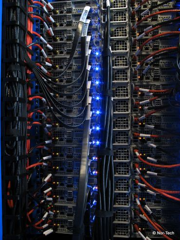 Close-up of a server rack with organized cables and glowing blue lights.