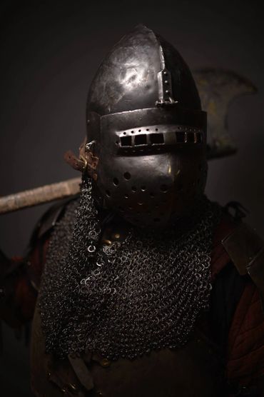 Medieval knight in full armor and chainmail with an axe on his back.