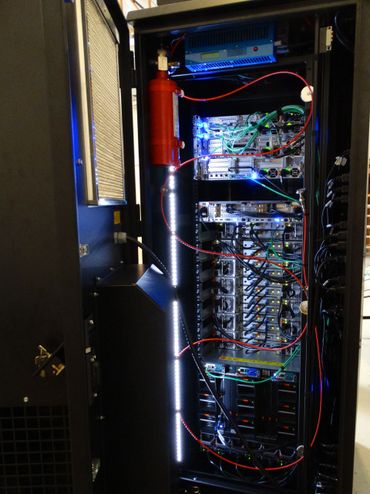 Open server rack with network equipment and red fire suppression cylinder.