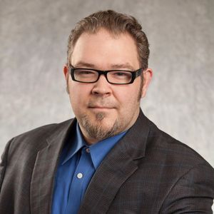 Professional man wearing glasses and a suit jacket with a blue shirt.