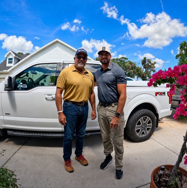 Two men standing in front of a white pickup truck.