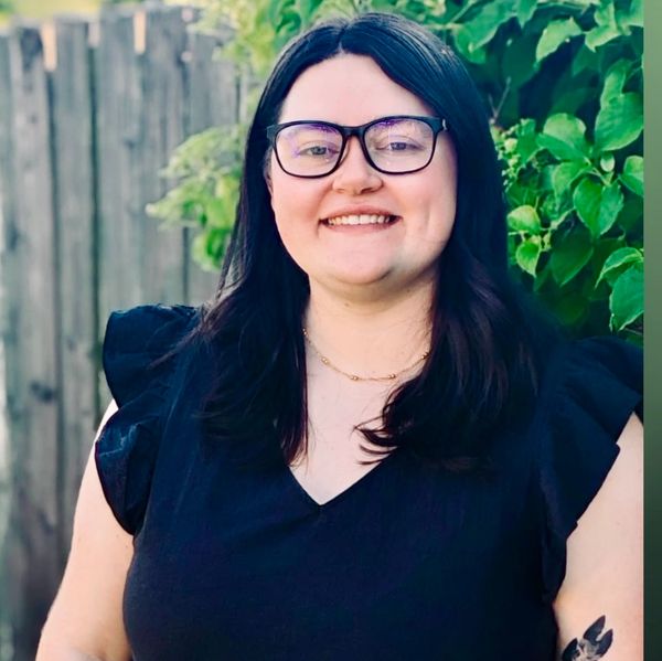Smiling woman with glasses and dark hair.
