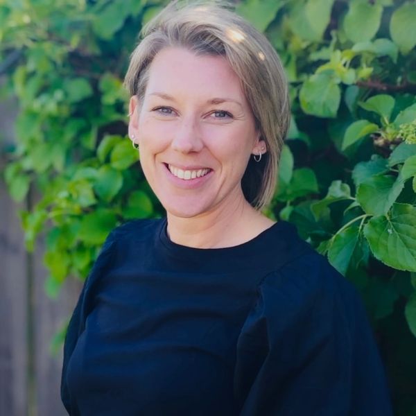 Smiling woman with short blonde hair outdoors.