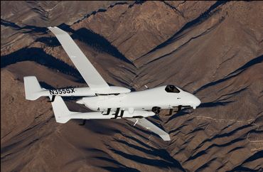 Air-to-air photo of prototype Northrup Grumman aircraft testing over Sierra Nevada mountains