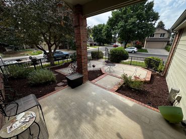 A suburban front porch with garden beds and outdoor seating.