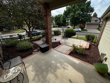A suburban front porch with garden beds and outdoor seating.