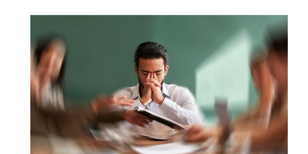 man with face in his hands during a work meeting