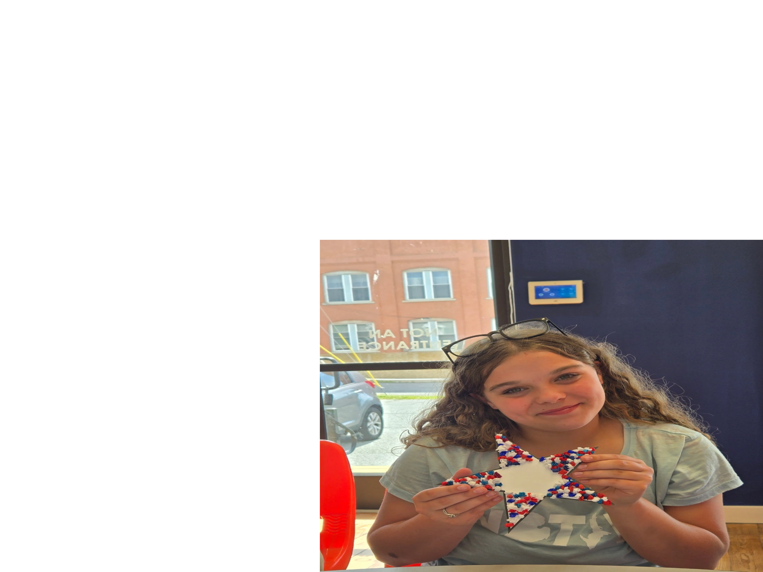 A girl smiling while holding a red, white, and blue star craft.