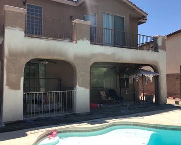 Stucco repair in progress on a two-story residential house with a backyard pool.