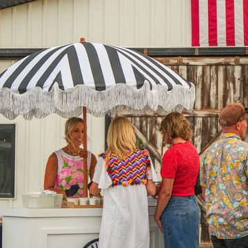 People at a striped umbrella ice cream stand.