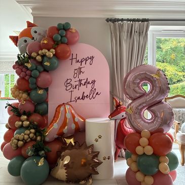 Birthday balloon setup with pink and green theme.