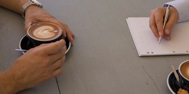 a coffee meeting between client and professional taking notes
