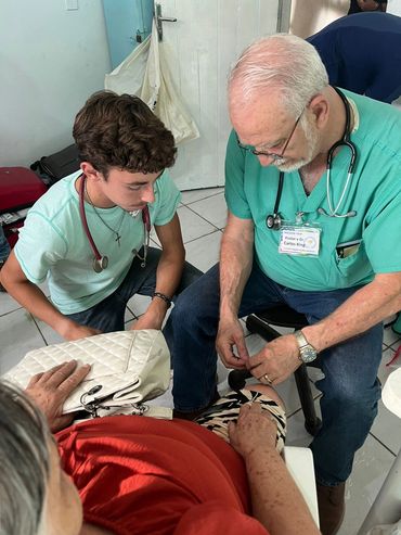 Two medical professionals examining an elderly patient in a clinic.