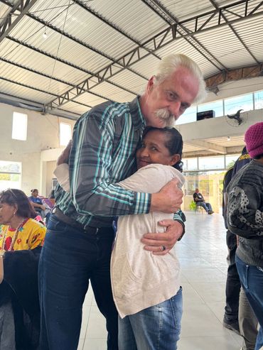 A warm embrace between two people in a bright indoor space.