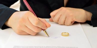 Mujer firmando documento de divorcio con anillo al lado