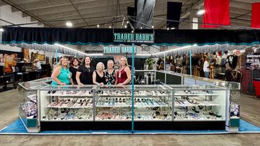 Five women at a jewelry booth in a market.