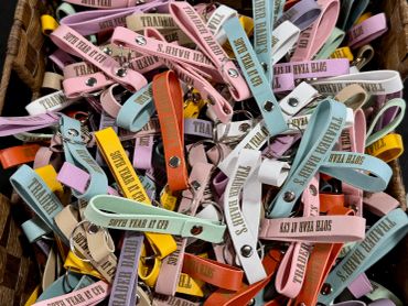 Assorted colorful wristbands with text, piled together.