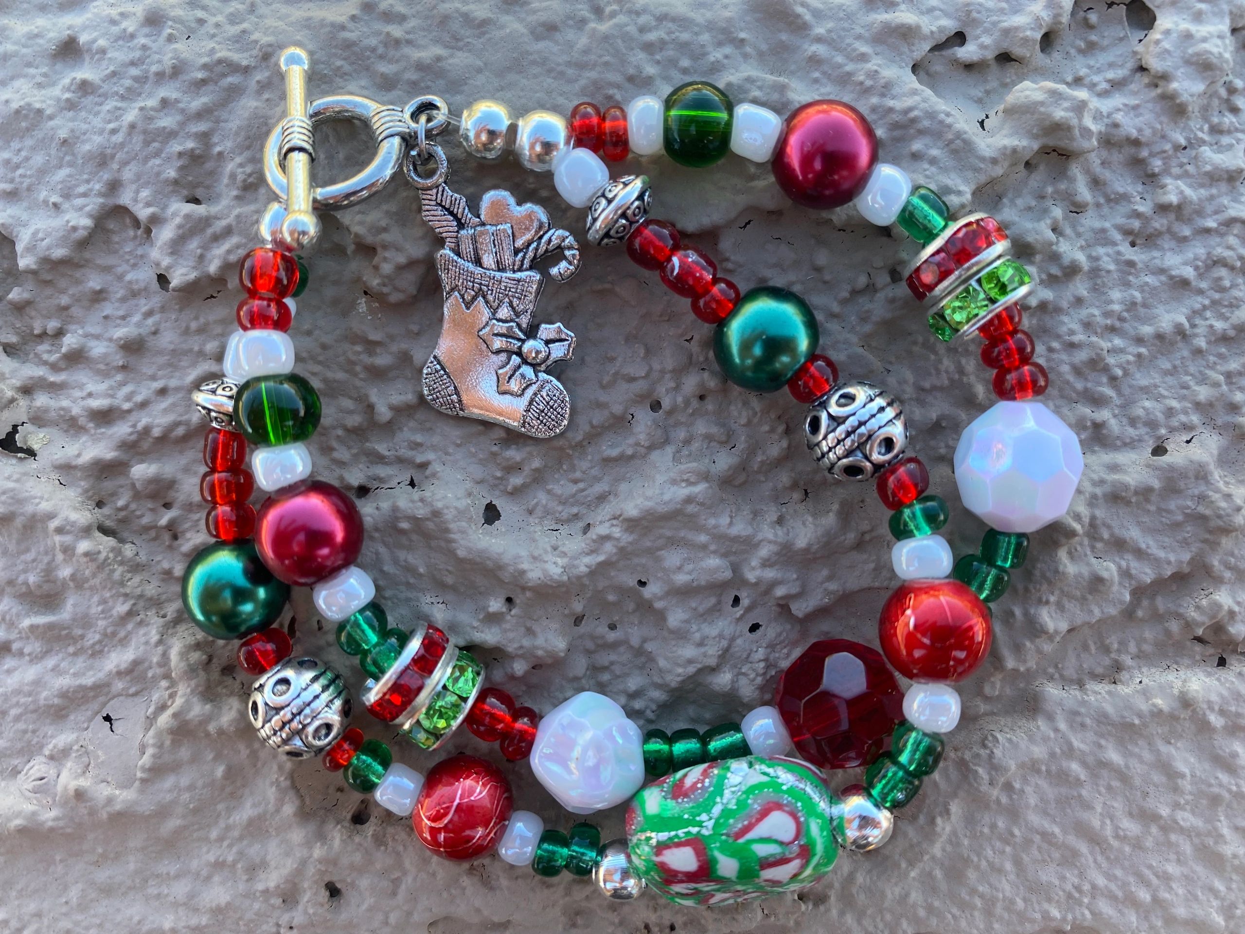 A must have fun Christmas bracelet with handcrafted clay beads and dangling stocking charm .